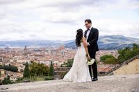 Bride and groom standing on top of the terrace overlooking the cityscape of Florence during their destination wedding in Tuscany