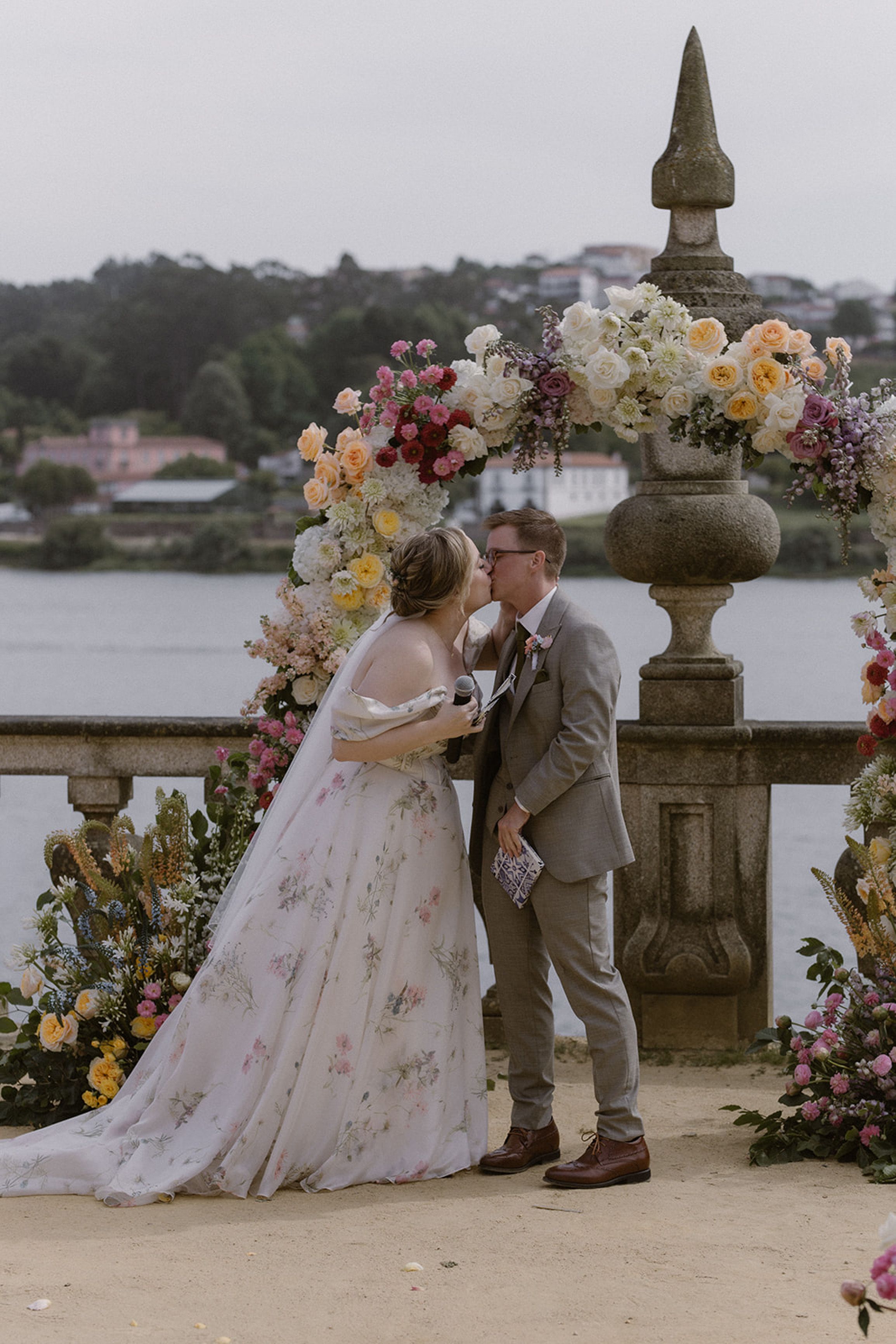 Newlyweds sharing their first kiss beneath a floral ceremony arch during a small wedding in Portugal