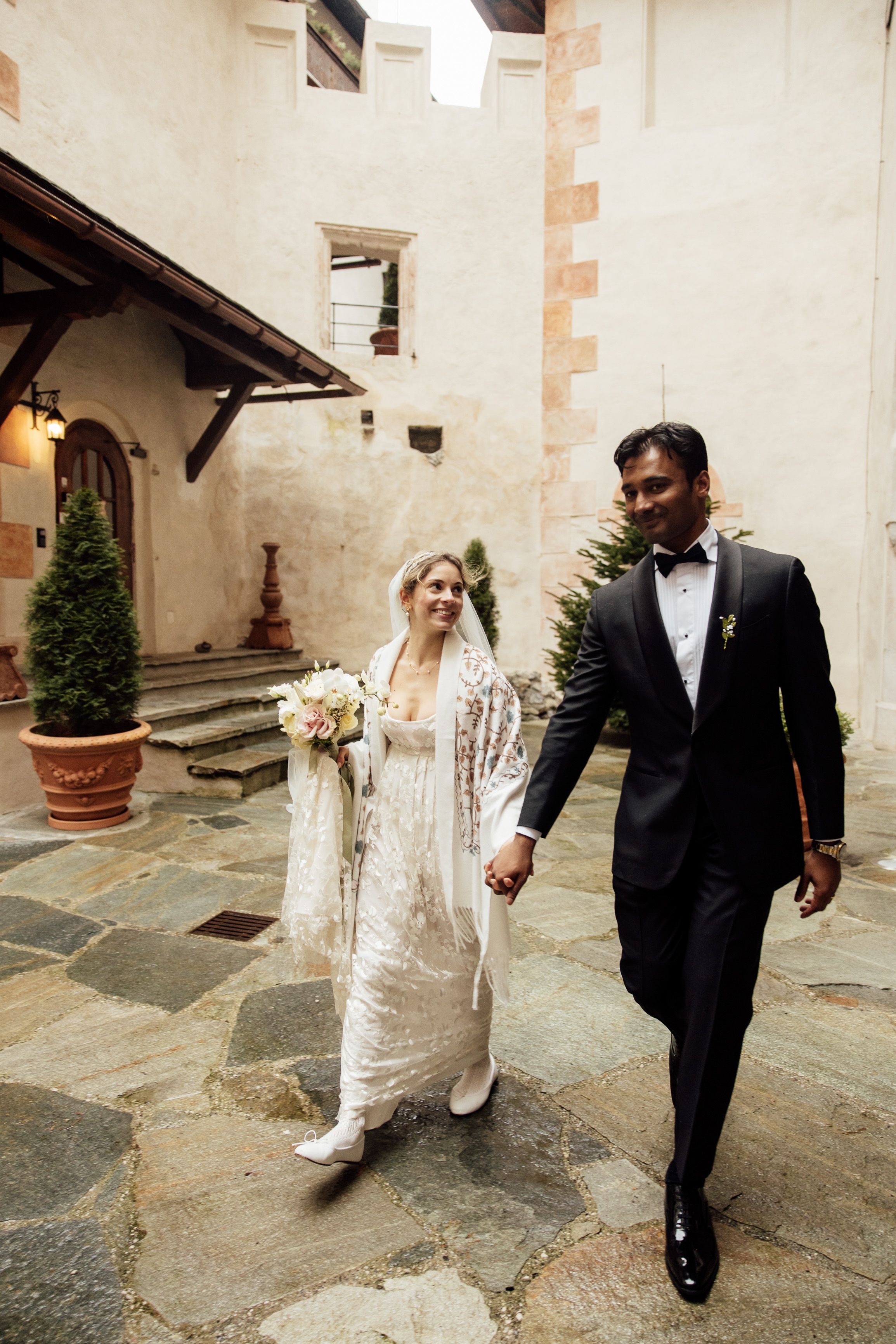 Bride and groom stroll through a castle courtyard after their ceremony at a small wedding in Austria