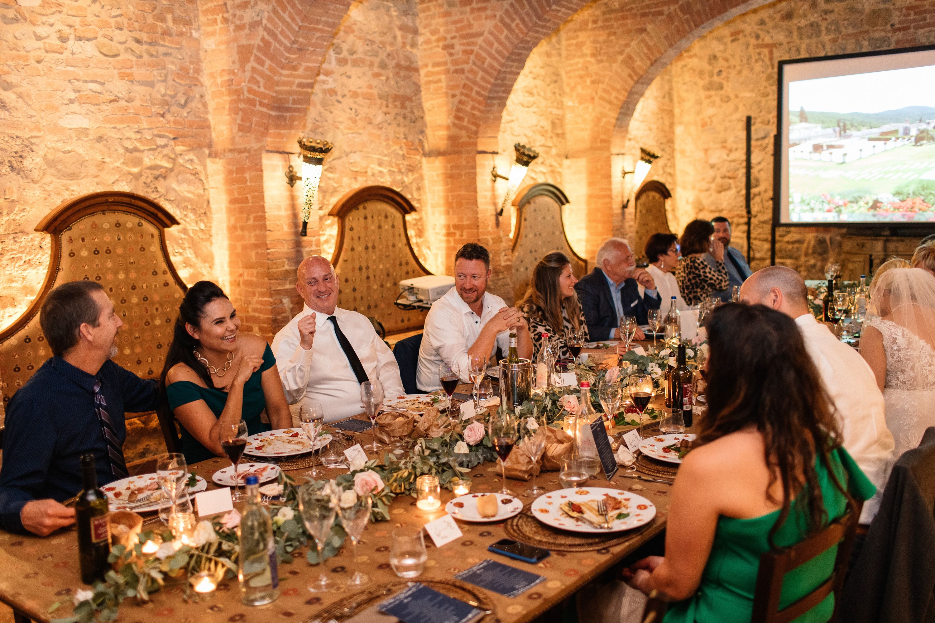 Family and friends share laughter at a rustic stone venue during a small wedding in Italy reception