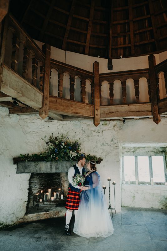 Bride wears blue dyed dress and groom wears Irish wedding attire, both inside a castle after their irish wedding ceremony