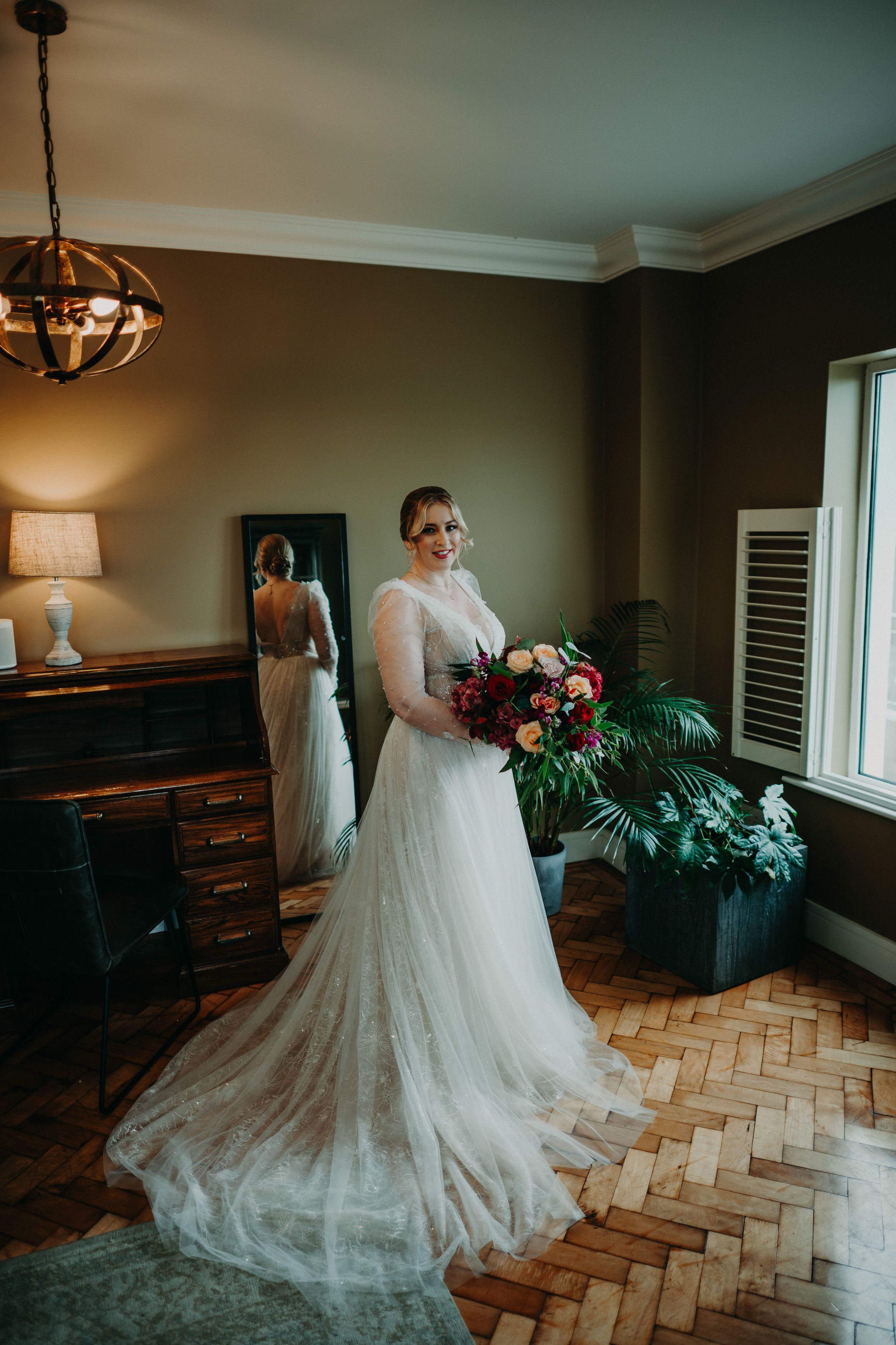 Bride posing with her bouquet in a cozy suite before a small wedding in Ireland