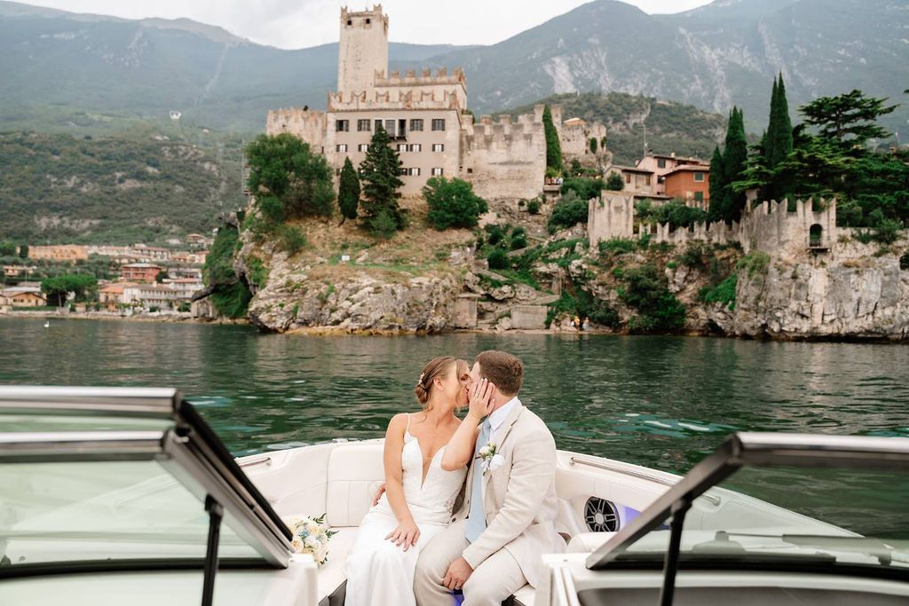 Newly eloped couple kiss during their boat ride along Lake Garda after the ceremony of their elopement in Italy