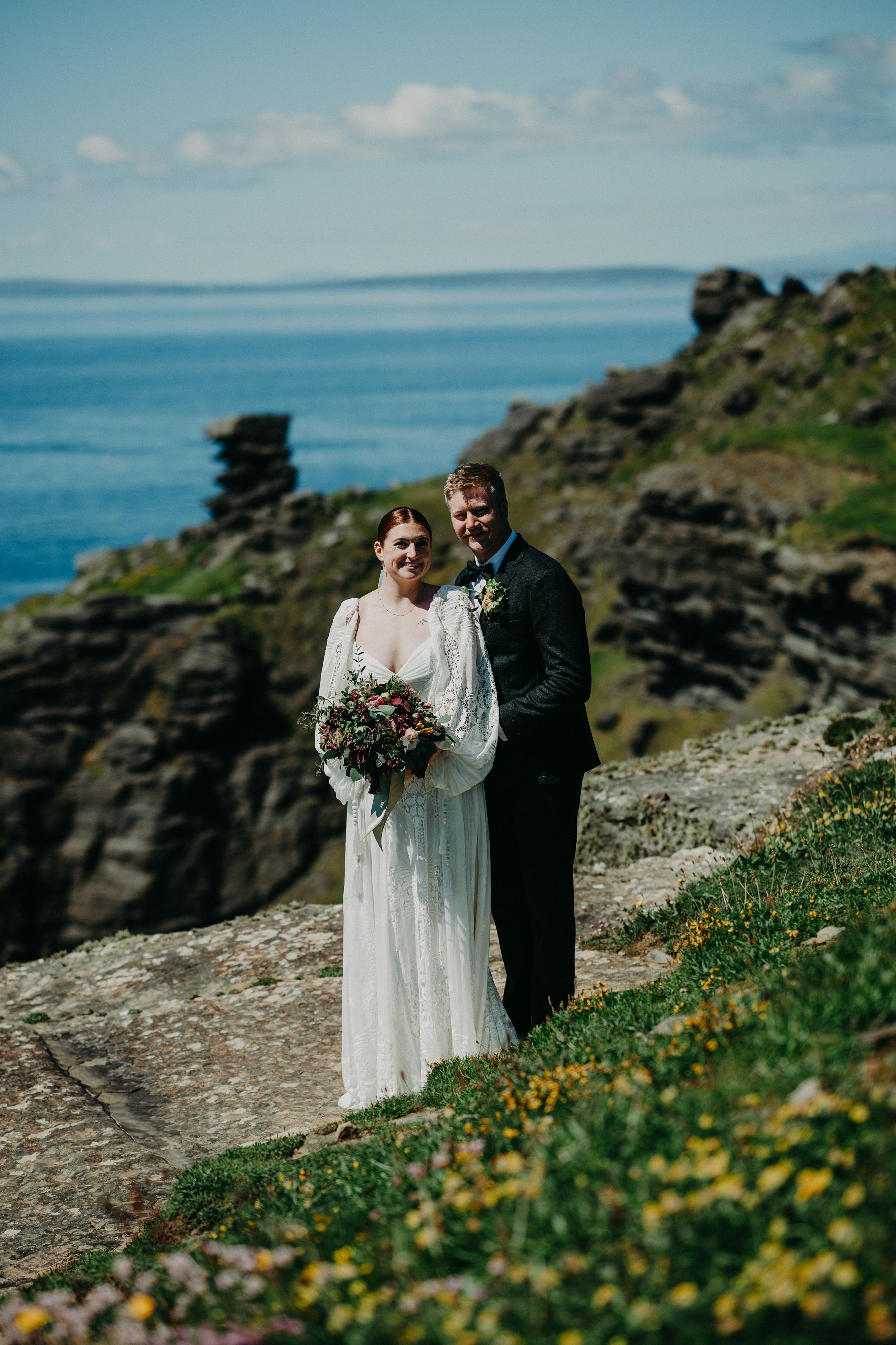 A couple standing on top of a captivating cliff after their intimate wedding in Ireland