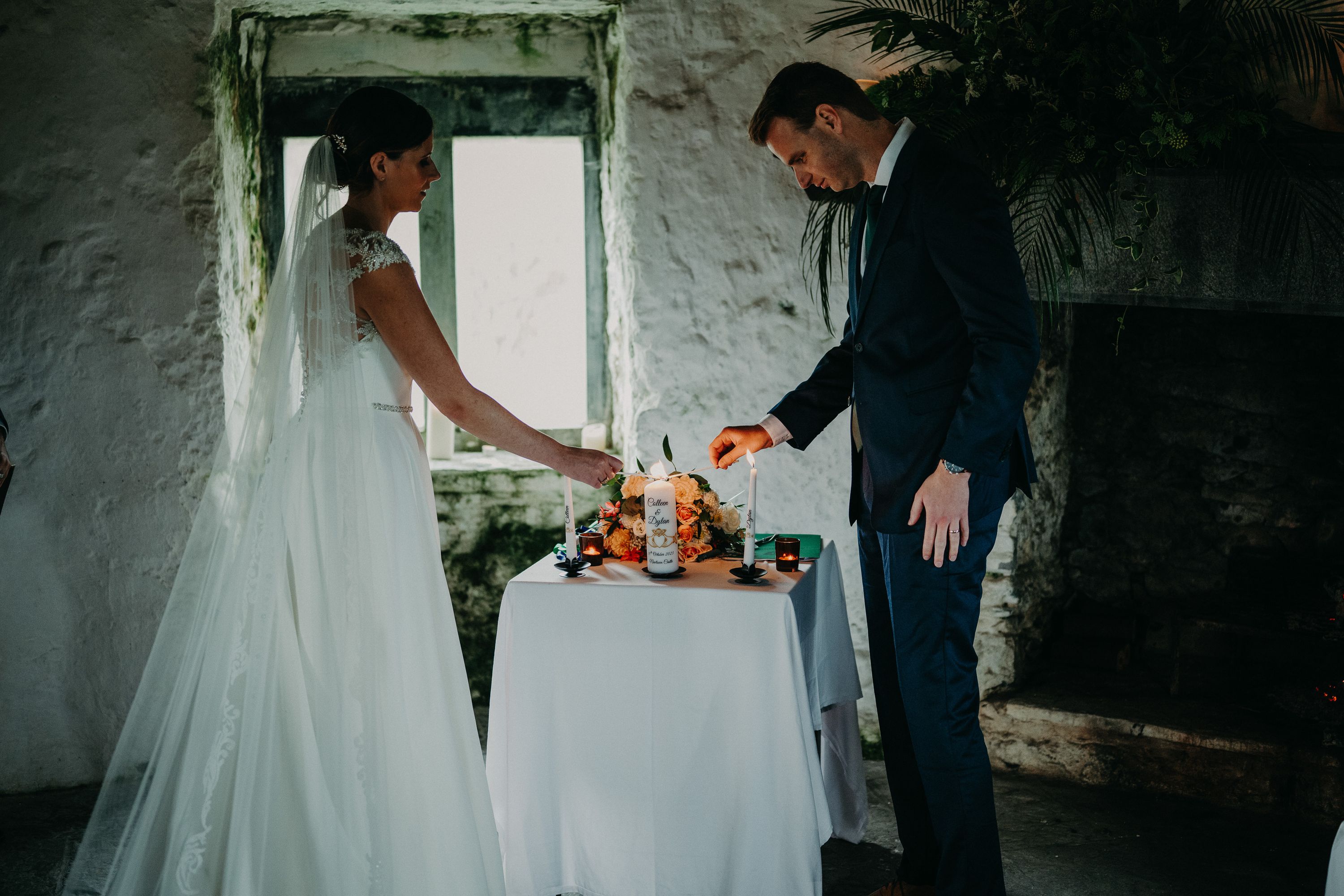 Bride and groom light a unity candle during a small wedding in Ireland inside a rustic castle room.