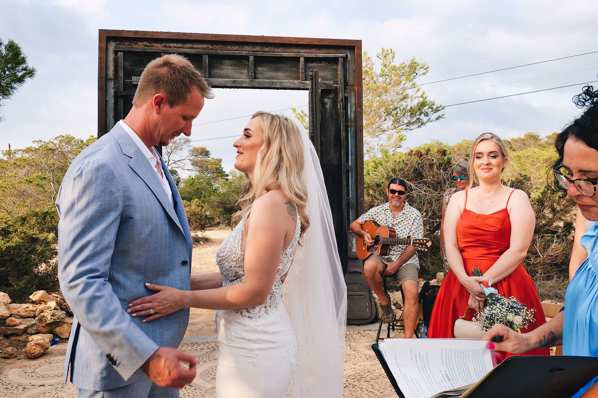 Bride and groom holding hands with their guest and celebrant during the ceremony of their Spanish wedding abroad