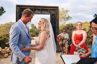 Bride and groom holding hands with their guest and celebrant during the ceremony of their Spanish wedding abroad