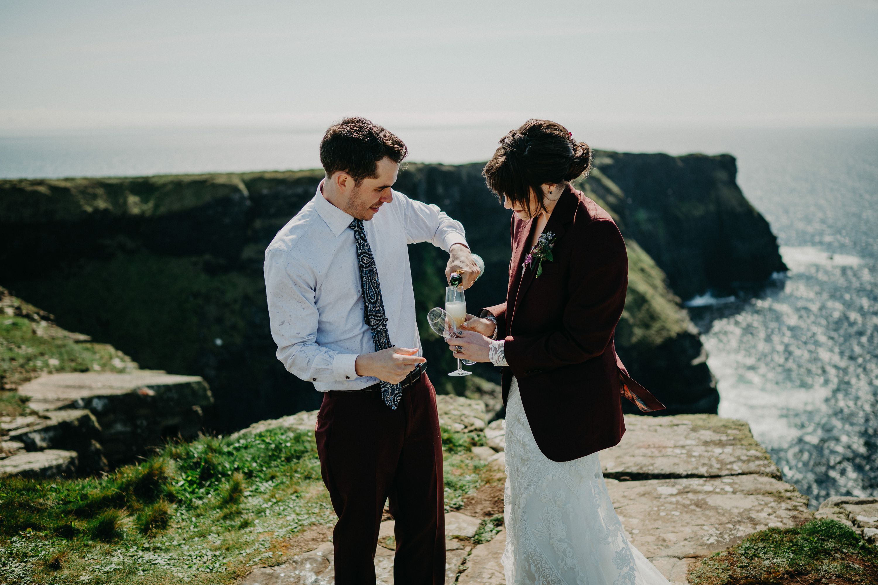 A groom pouring a drink for her bride after their intimate wedding in Ireland