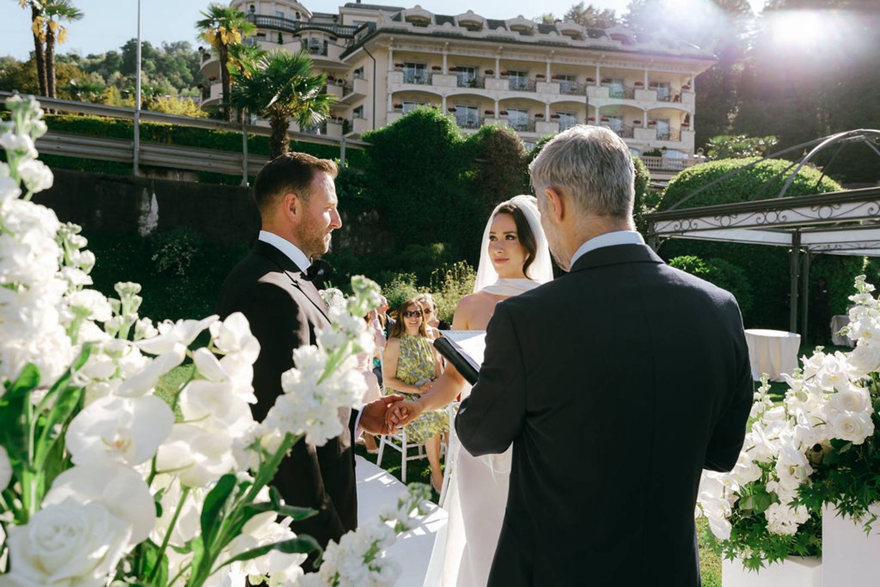 Bride and groom exchanging vows surrounded by white florals at a small wedding in Italy