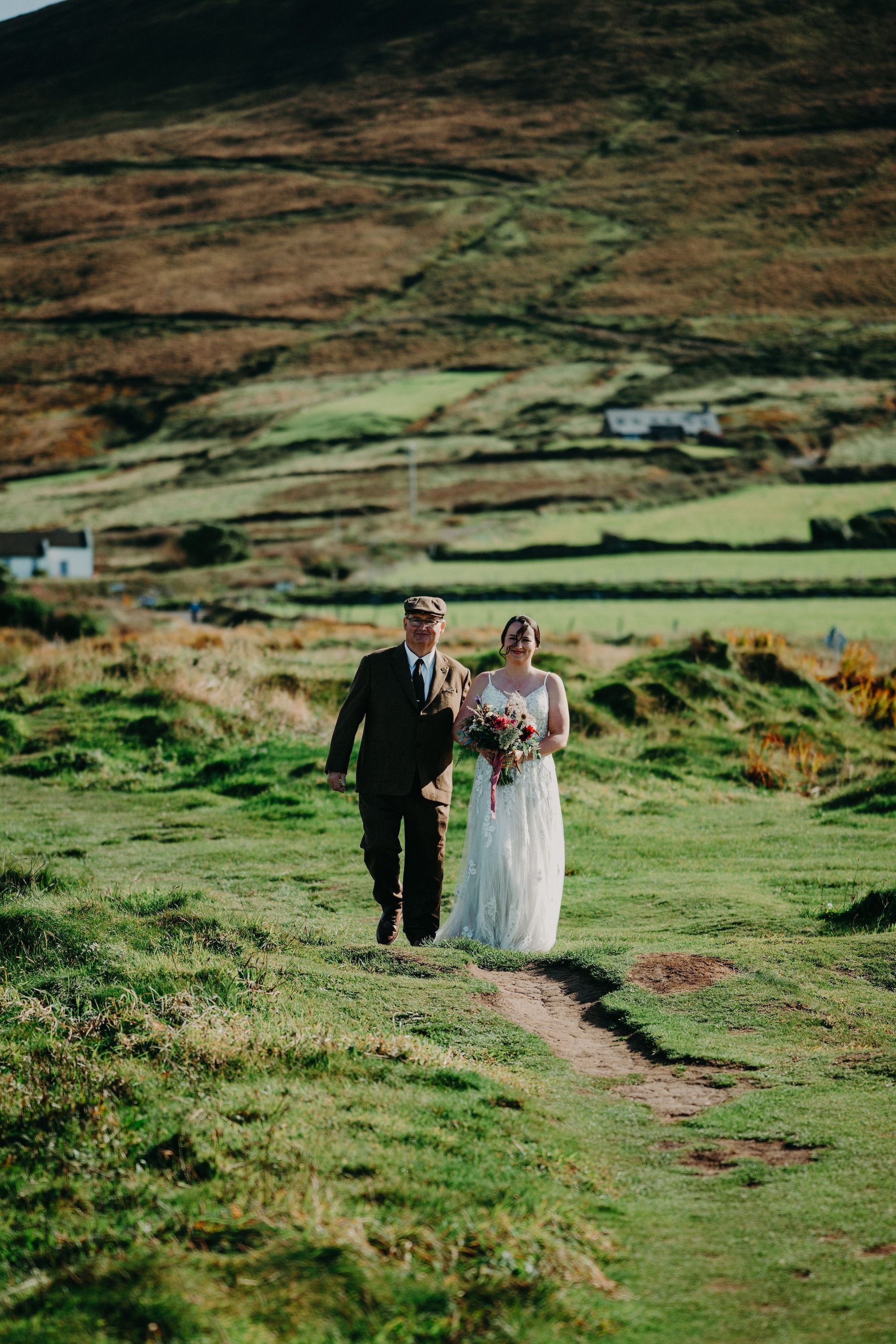 Bride walks down her unique aisle in the midst of the meadows of a cliff in Kerry during her elopement in Ireland