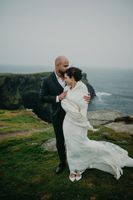 Bride and groom pose romantically atop the Cliffs of Moher for the photoshoot of their small wedding in Ireland