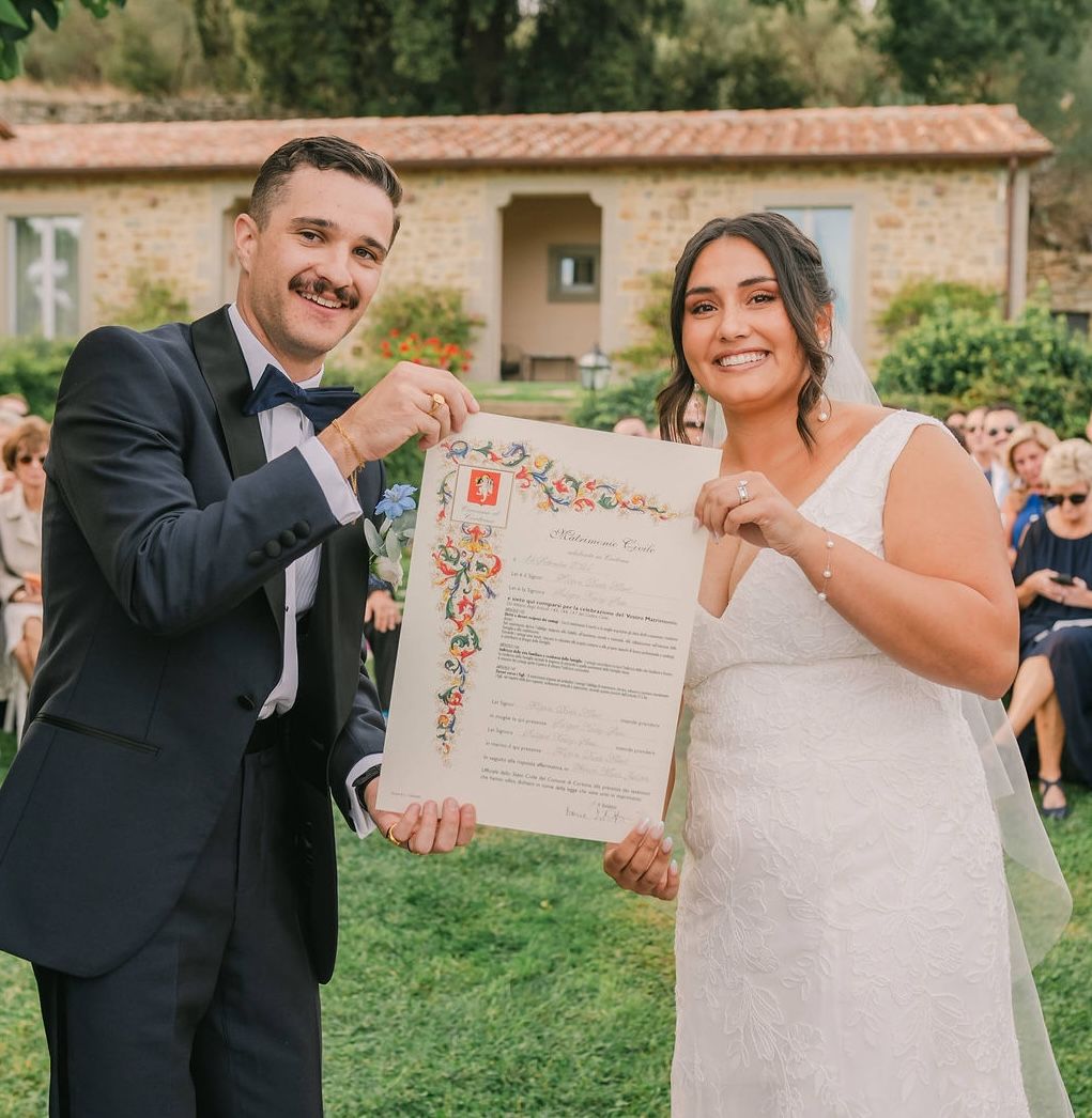 Bride and groom smiling as they hold a document evidencing their destination wedding in Italy