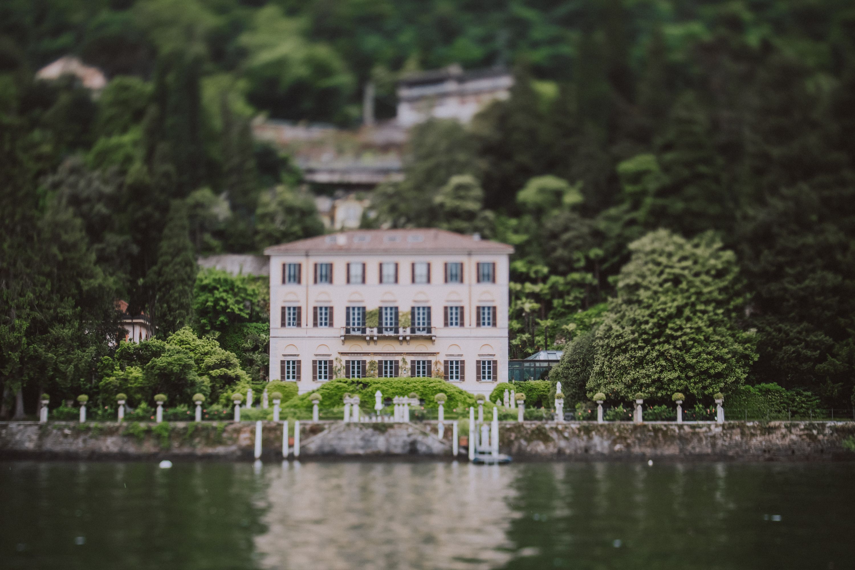 A lakeside villa along Lake Como with garden in front and Italian hills in the background