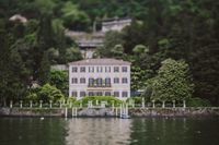 A lakeside villa along Lake Como with garden in front and Italian hills in the background