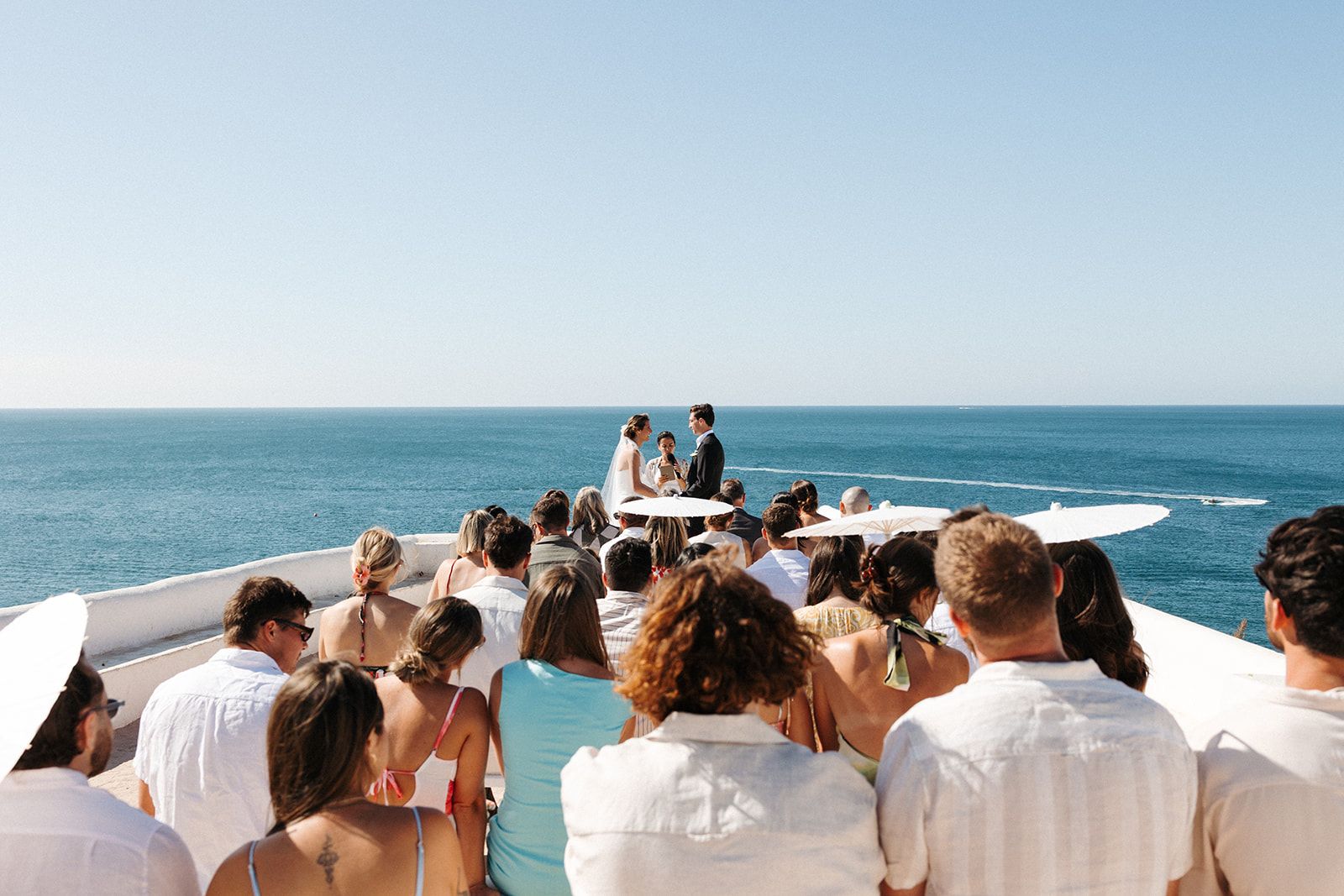 An intimate wedding in Portugal with the bride and groom in front of their guests on a clifftop outdoor ceremony in Algarve