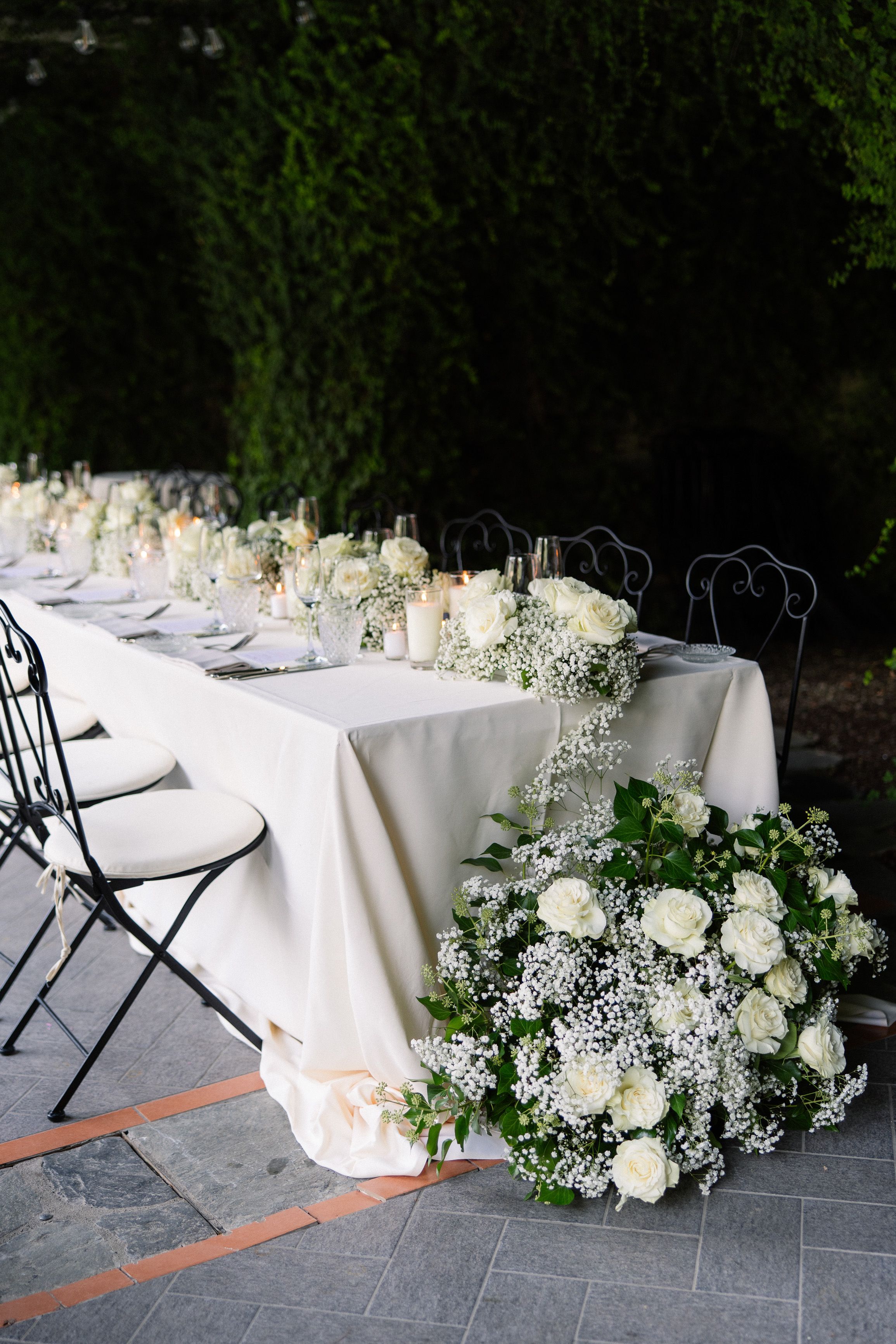 Romantic reception table with white roses and candles at an intimate wedding in Italy