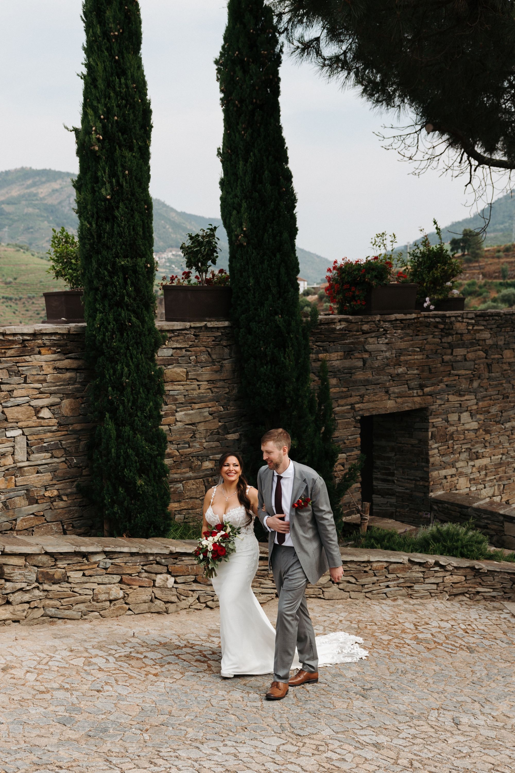 Bride and groom walking along a cobbled street with tall trees in the background during their small wedding in Portugal
