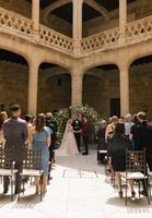 Bride and groom holds hands in front of their guests in a castle's courtyard during their destination wedding in Spain