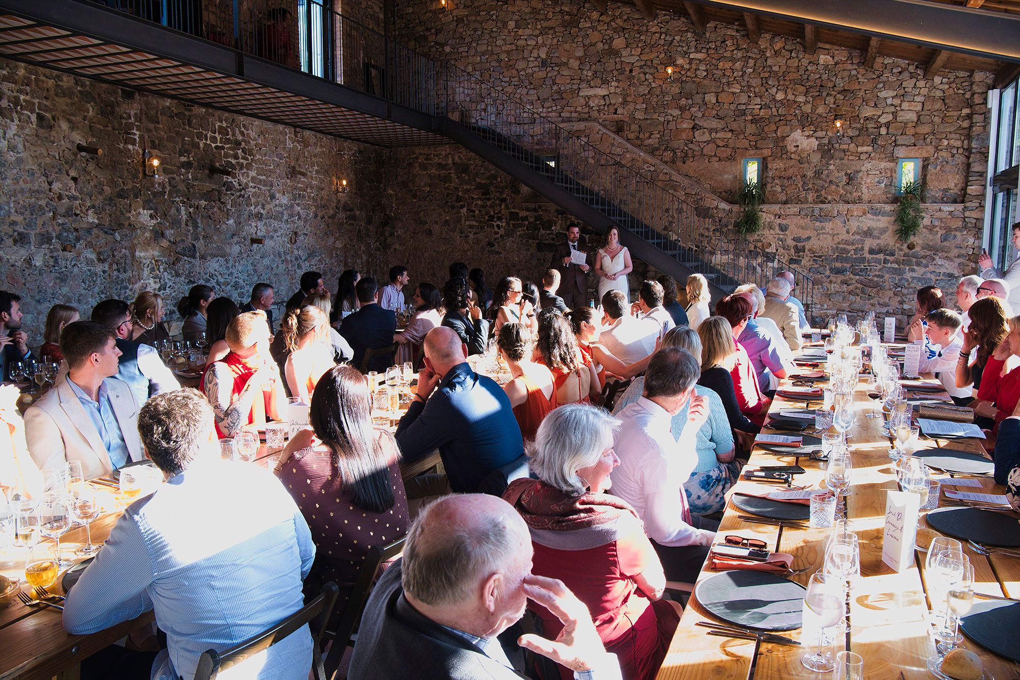 Bride and groom deliver a speech during the reception of their destination wedding in Spain in a rustic event room