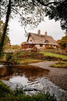 A thatched-roof cottage in a nature park in autumn colors with a lake