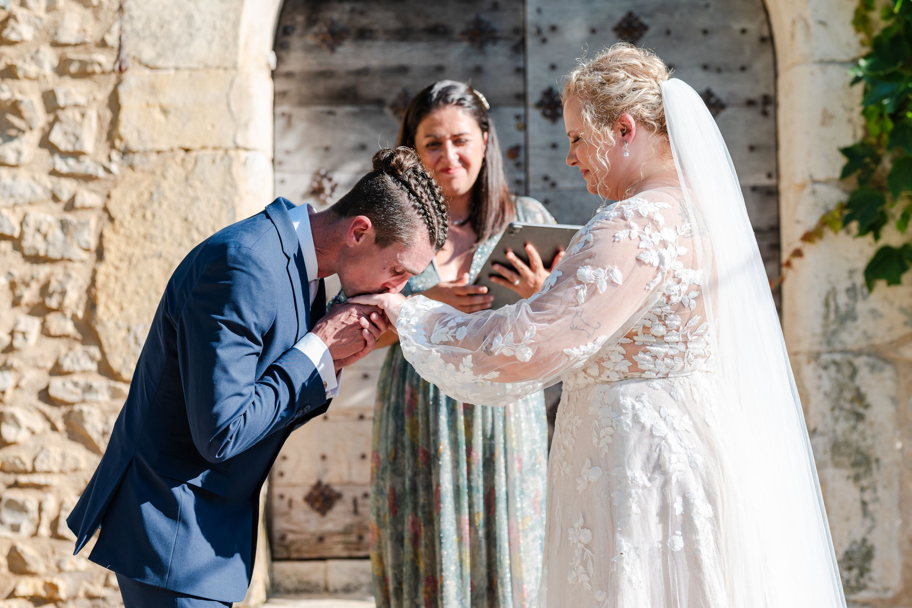 Groom kissing bride's hand during heartfelt vows at a small wedding in France