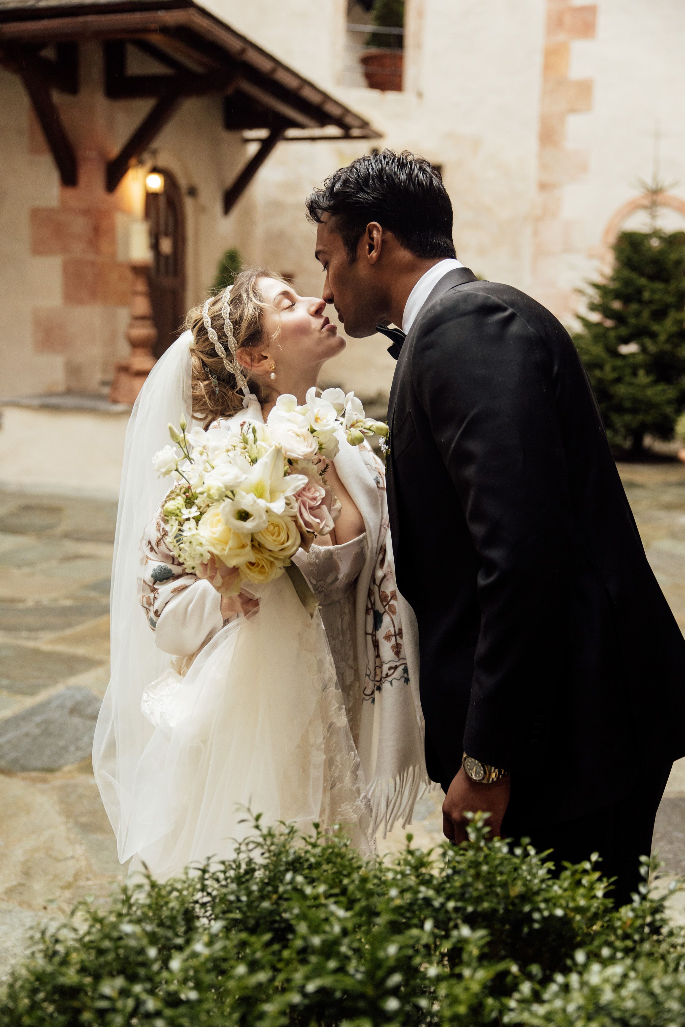 Bride and groom share a romantic kiss in a castle courtyard during an intimate wedding in Austria