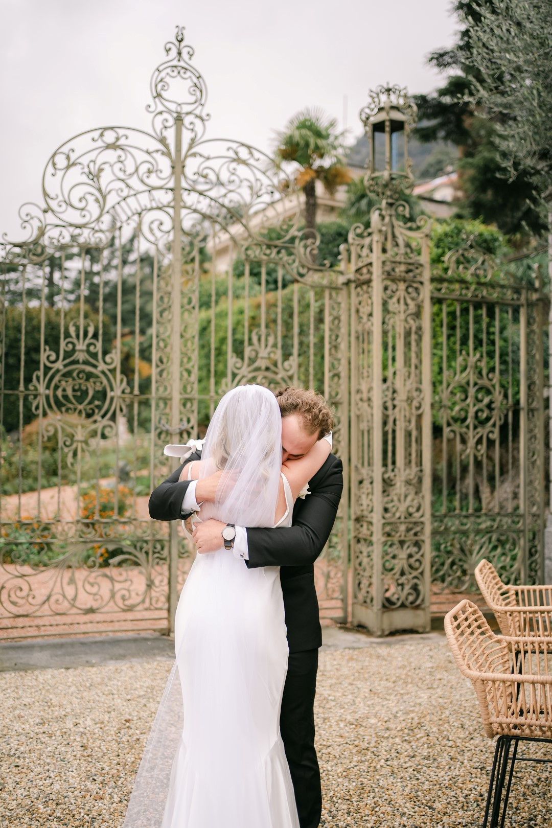 A groom seeing his bride for the first time with an elegant garden gate behind them during their intimate wedding in Italy