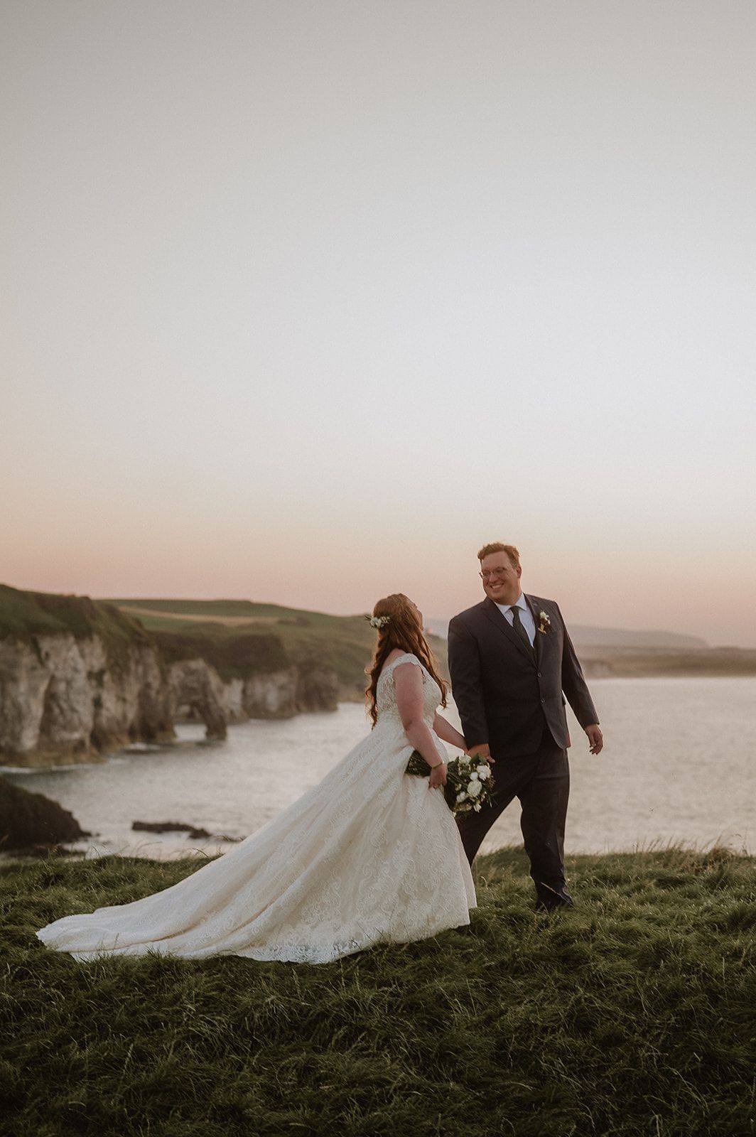 Newlyweds look at each other during their clifftop photoshoot after their vow renewal in ireland