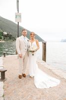 Bride and groom look at the camera with Lake Garda and a mountain in the background during their elopement in Italy