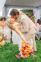 Bride holds an orange-themed bouquet while kissing the groom during their micro wedding in Italy