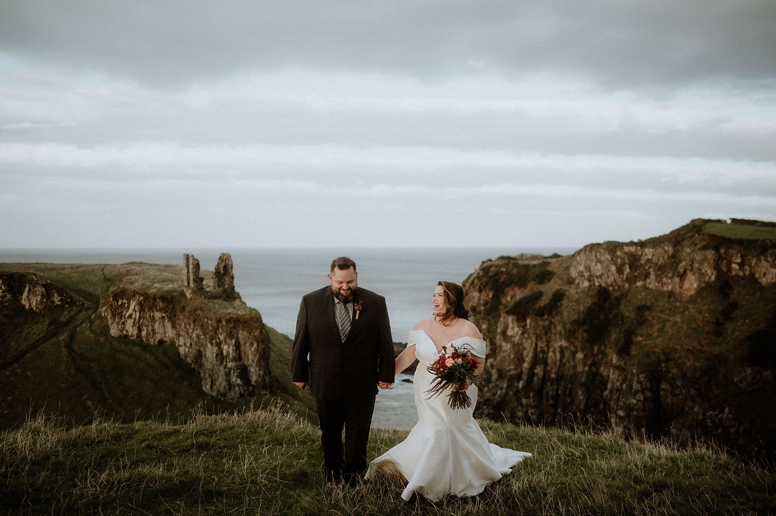 Bride and groom laughing on the cliffs of Antrim during their autumn elopement in Northern Ireland