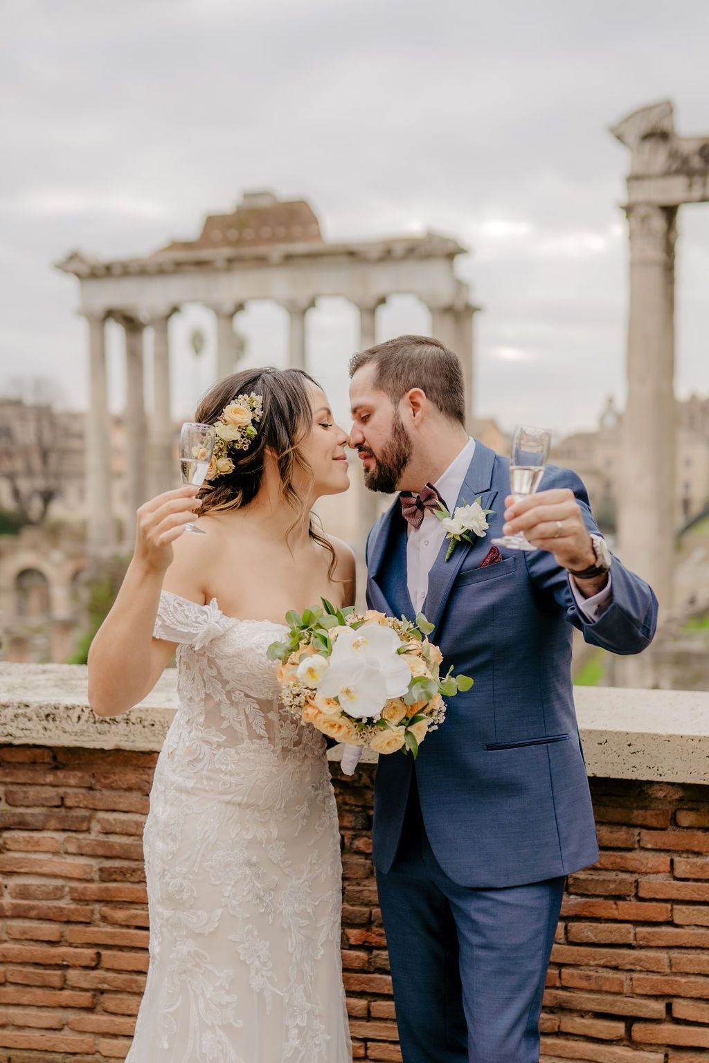 Bride and groom holds wine glasses as after their Italian elopement ceremony atop a terrace overlooking Pantheon in Rome