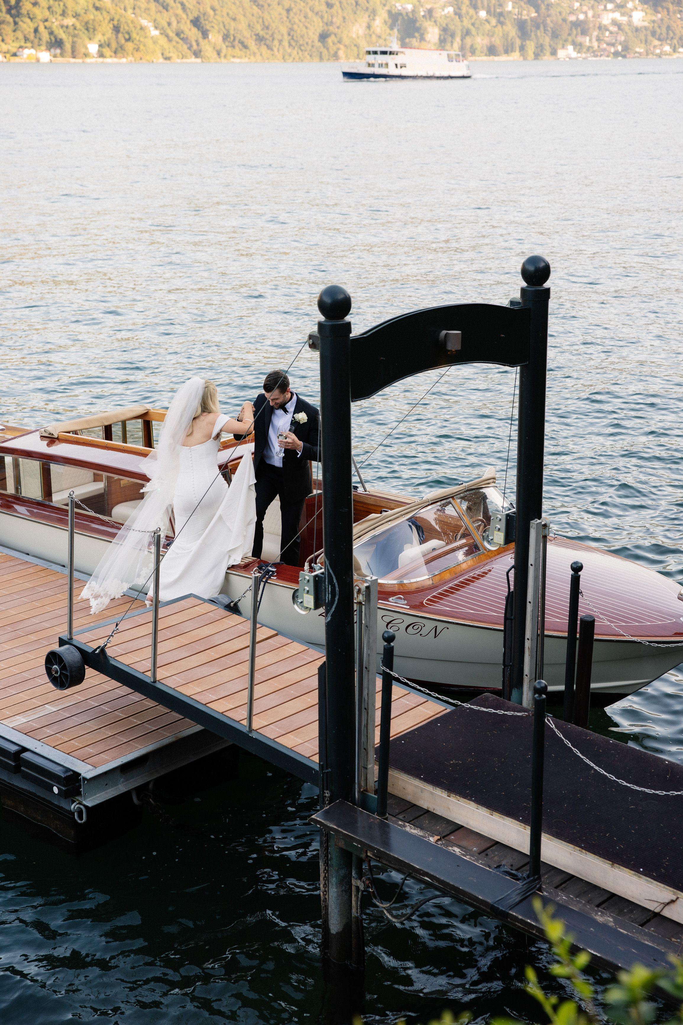 A bride and groom boarding a boat for their small wedding in Italy set beside a lake