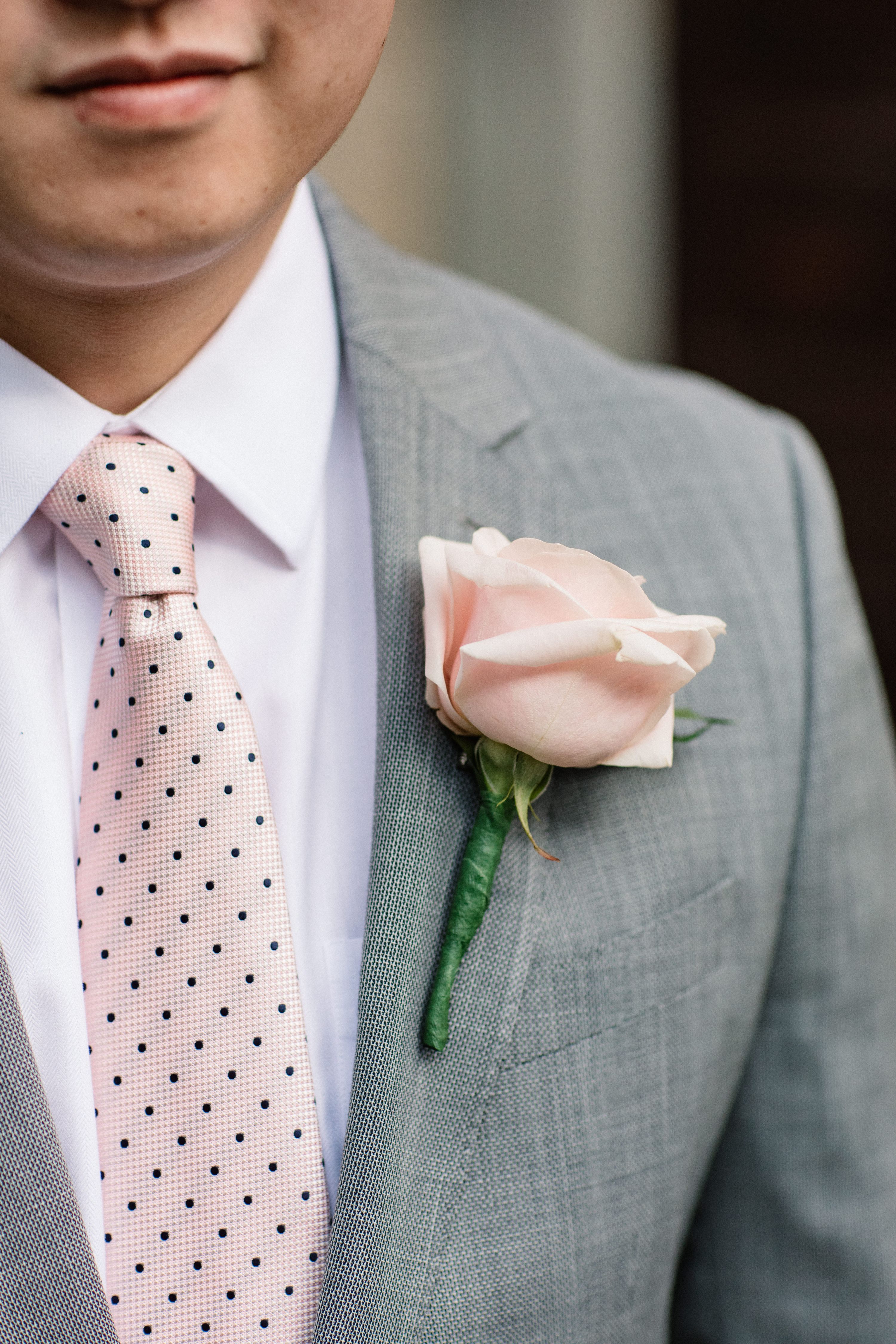 Close-up of groom wearing a blush rose boutonniere at a small wedding in Italy