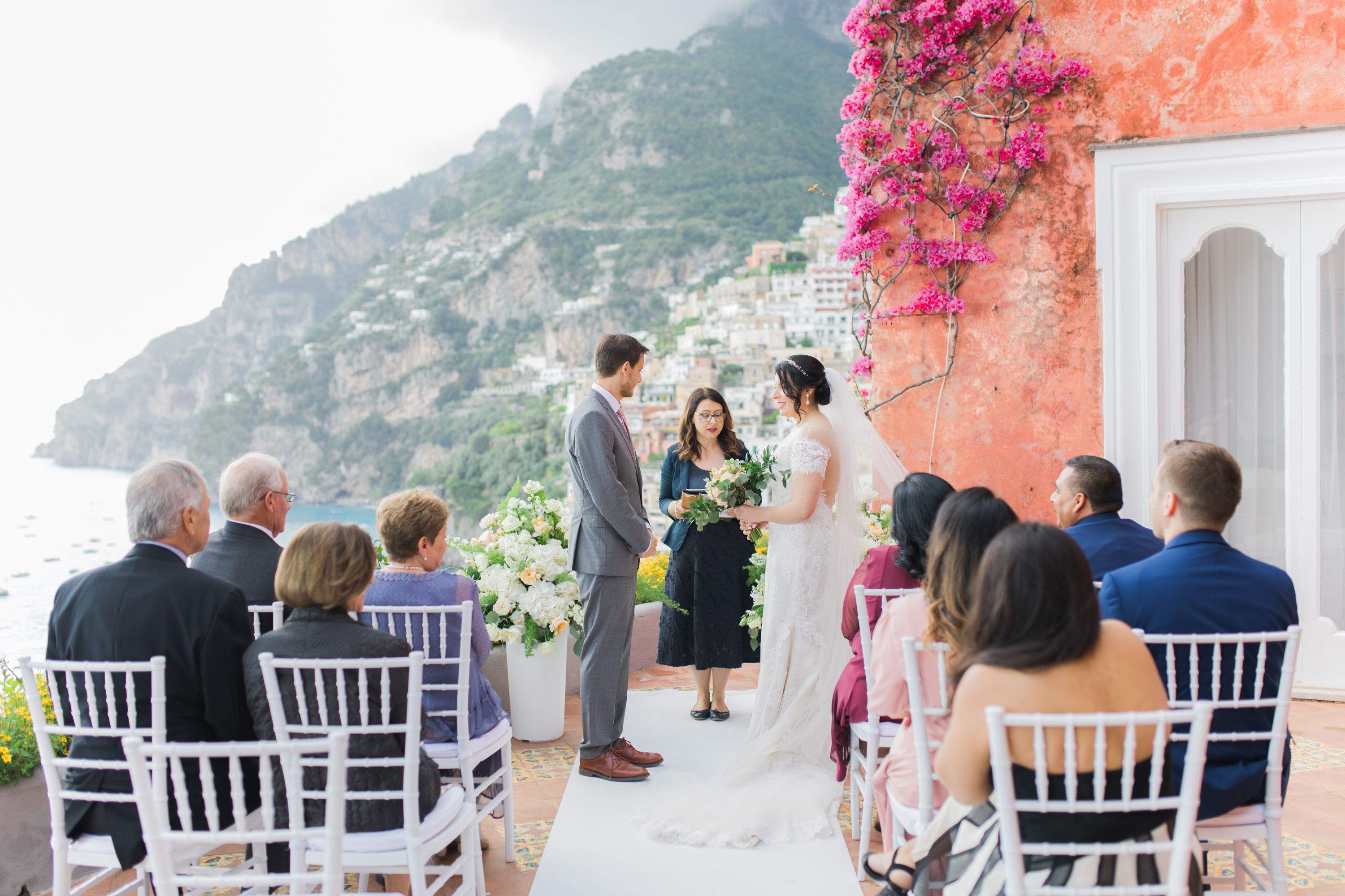 Amalfi Coast in full view while a couple exchanges vows atop an outdoor terrace of a hotel