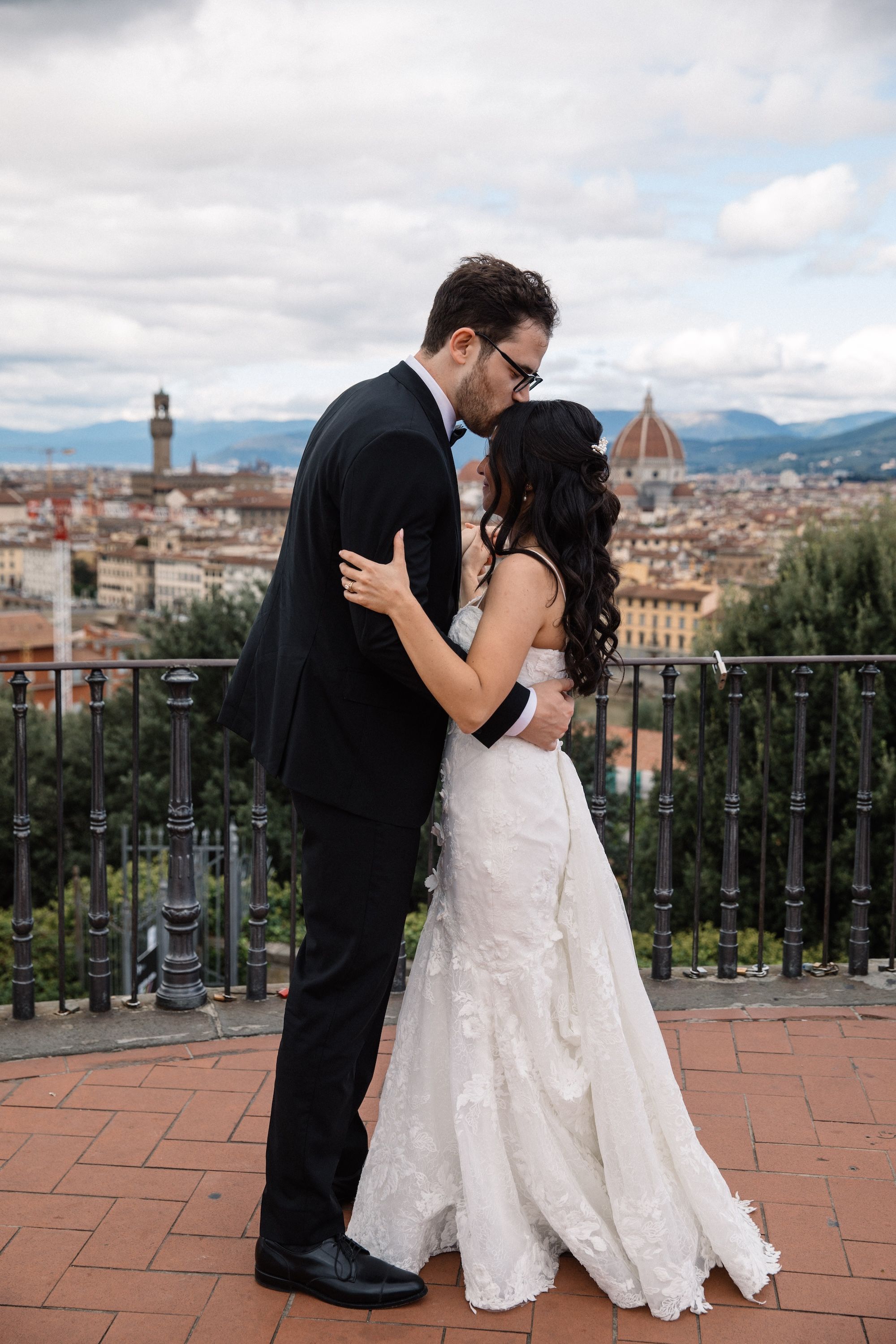 Groom kisses his bride during the photoshoot of their vow renewal in Italy with the Florence skyline in the background