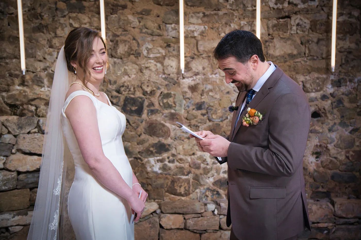 Couple smiling while the groom reads his vows during the ceremony of their destination wedding in Spain