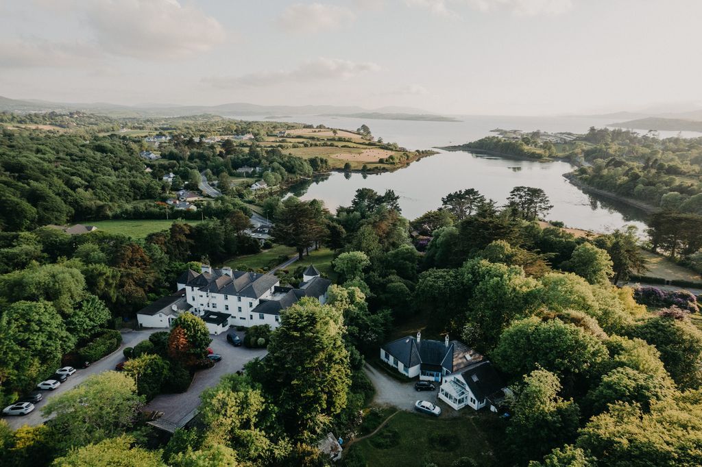 The green landscapes of Ireland, consisting of tall trees, forests, a wide lake, and large villas