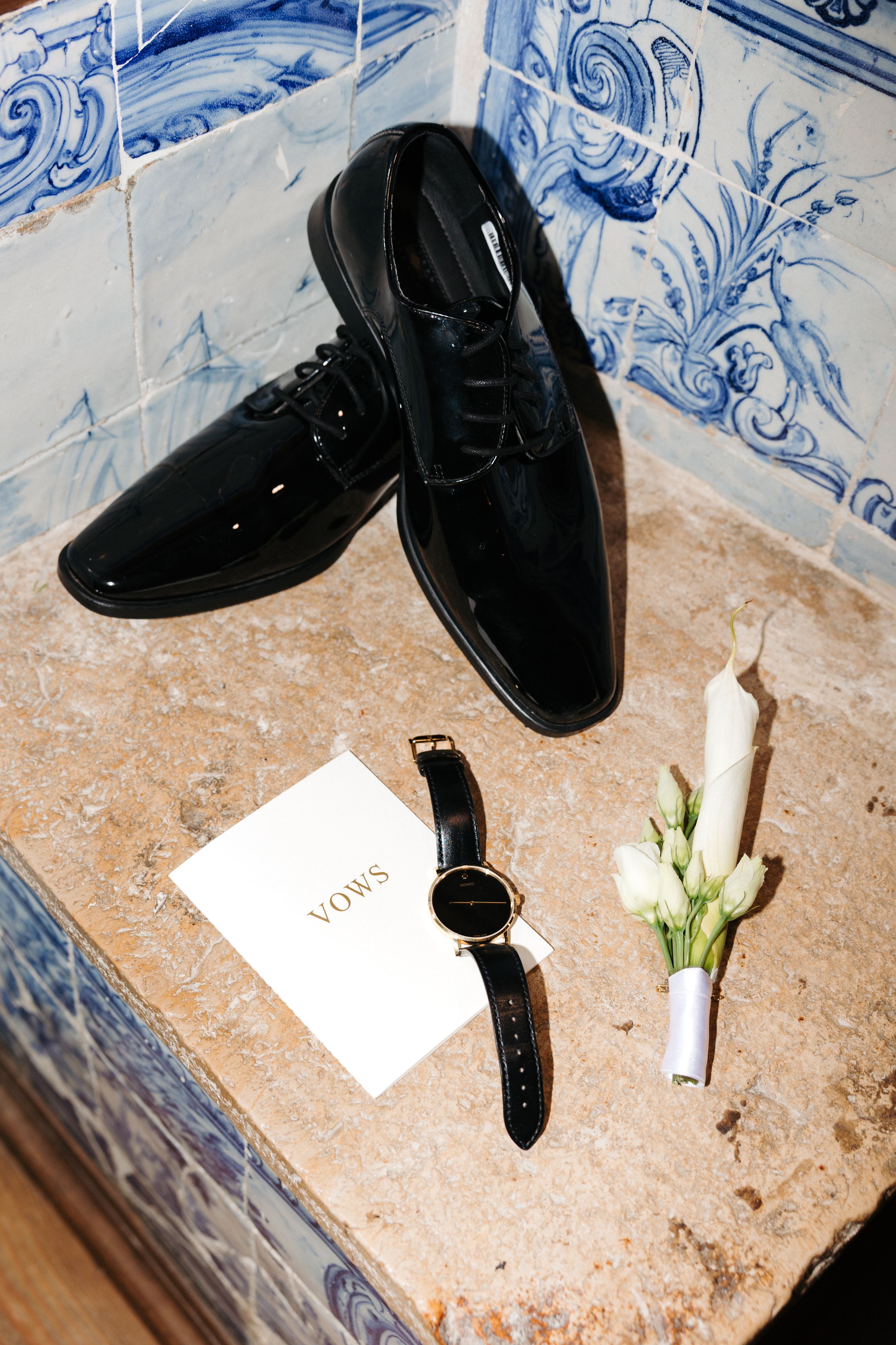 Detail shot of groom's vows and buttonhole in front of Portuguese tiles