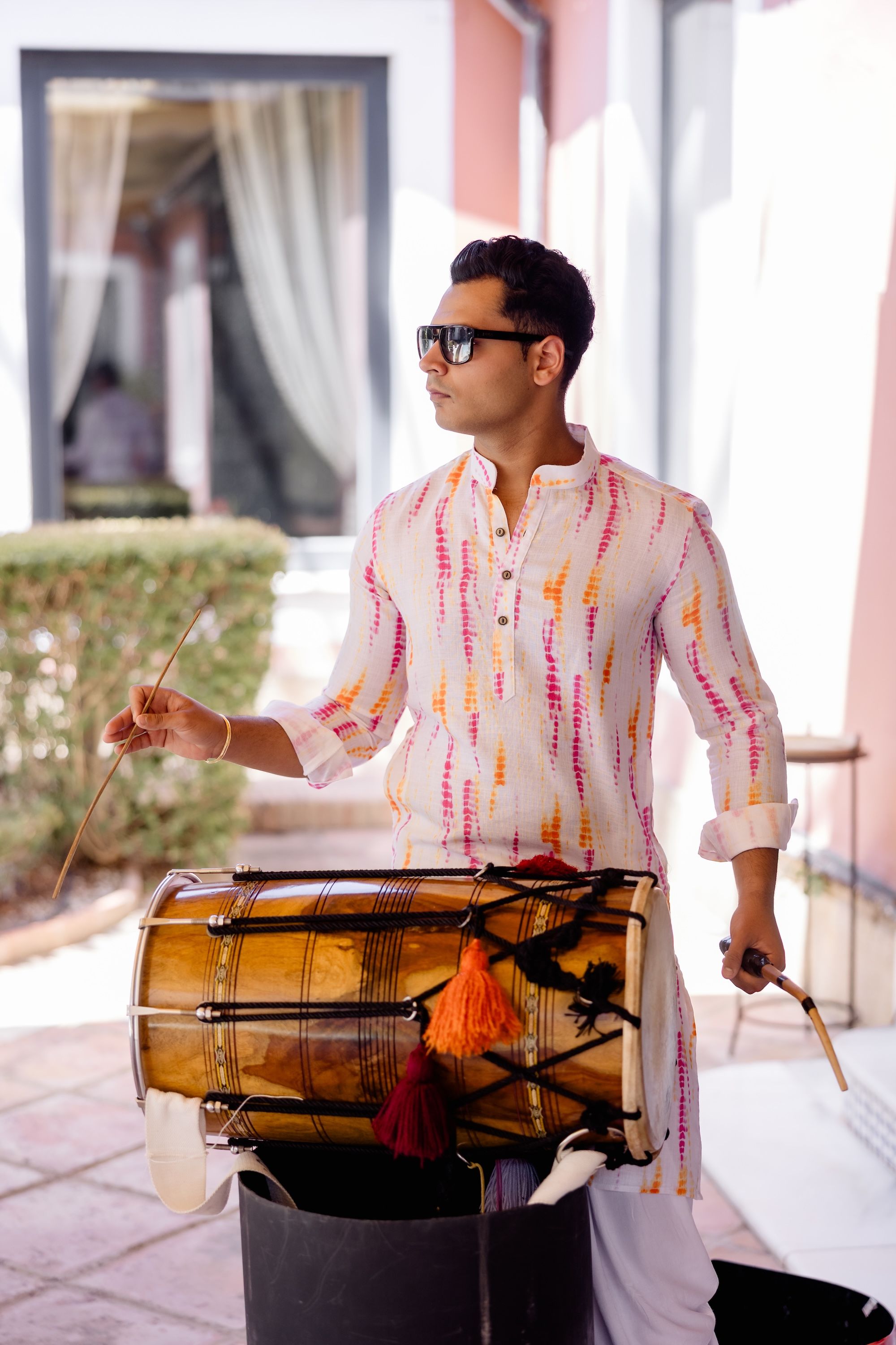 A percussion musician wearing casual long-sleeved top and sunglasses performing during a destination wedding in Spain