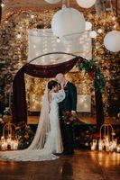 Bride and groom pose for their photoshoot, in the middle of their round wedding arch adorned with flowers and greens