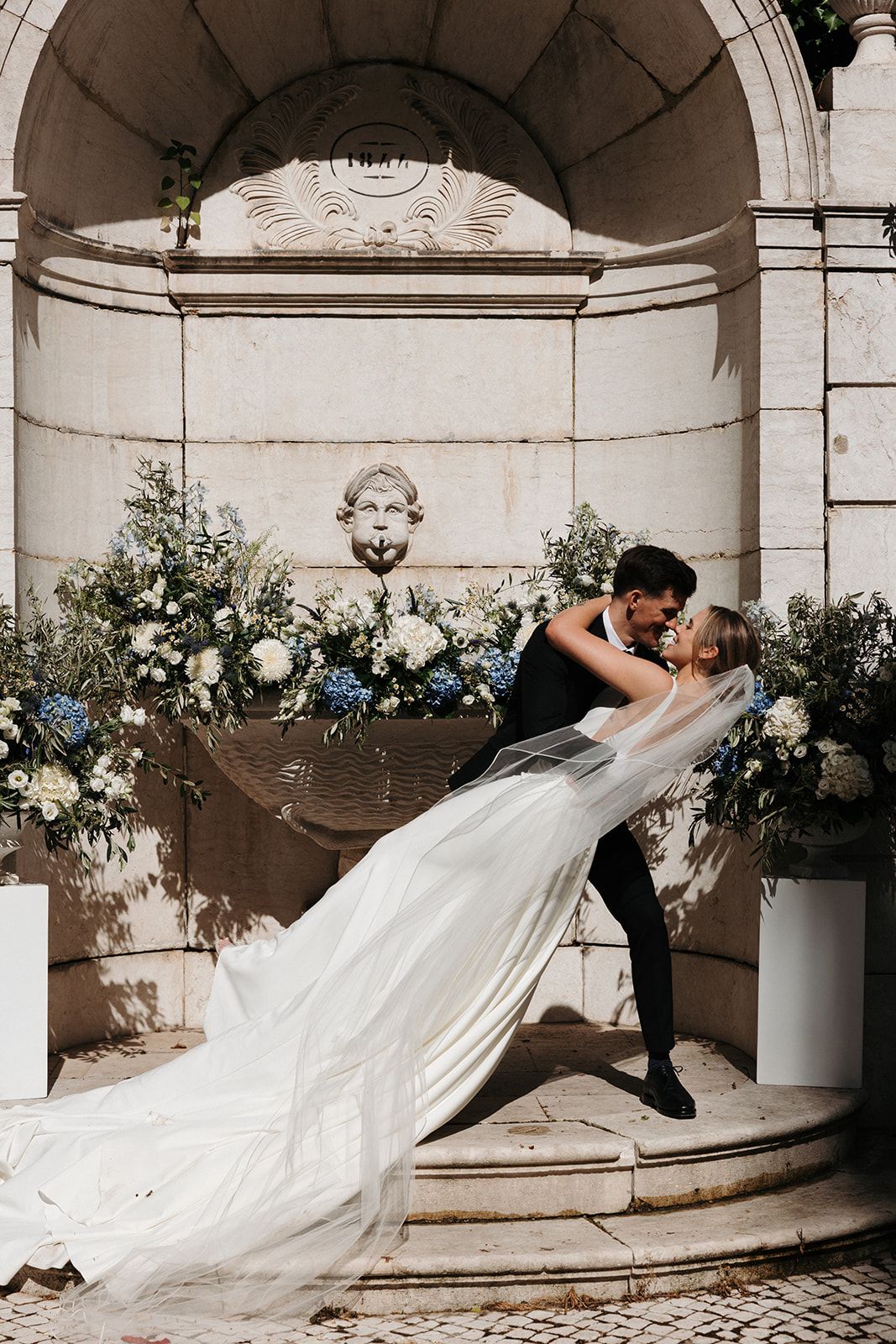Bride and groom kissing under a stone gazebo for the ceremony of their destination wedding in Portugal