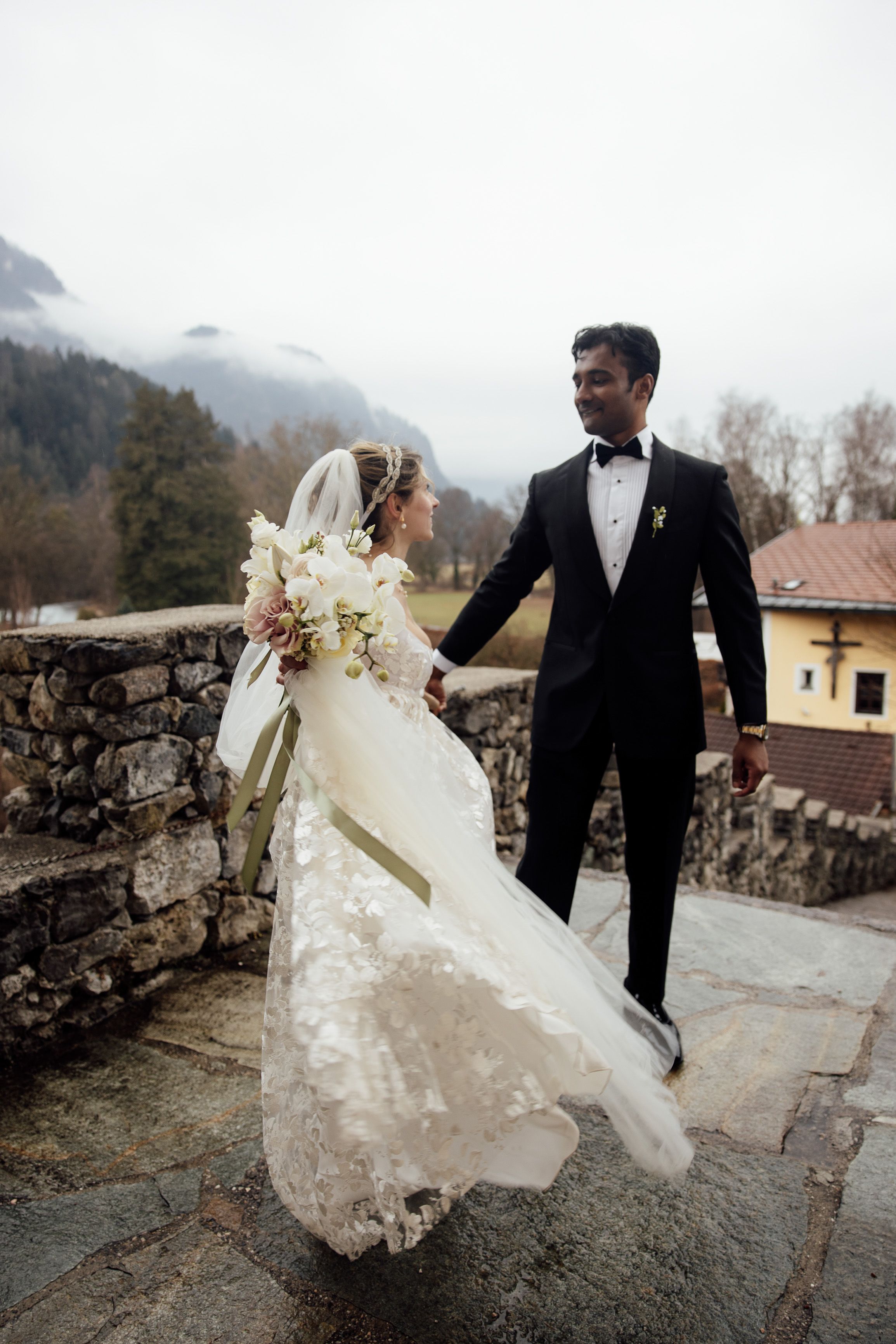Newlyweds share a joyful moment overlooking alpine scenery after their small wedding in Austria