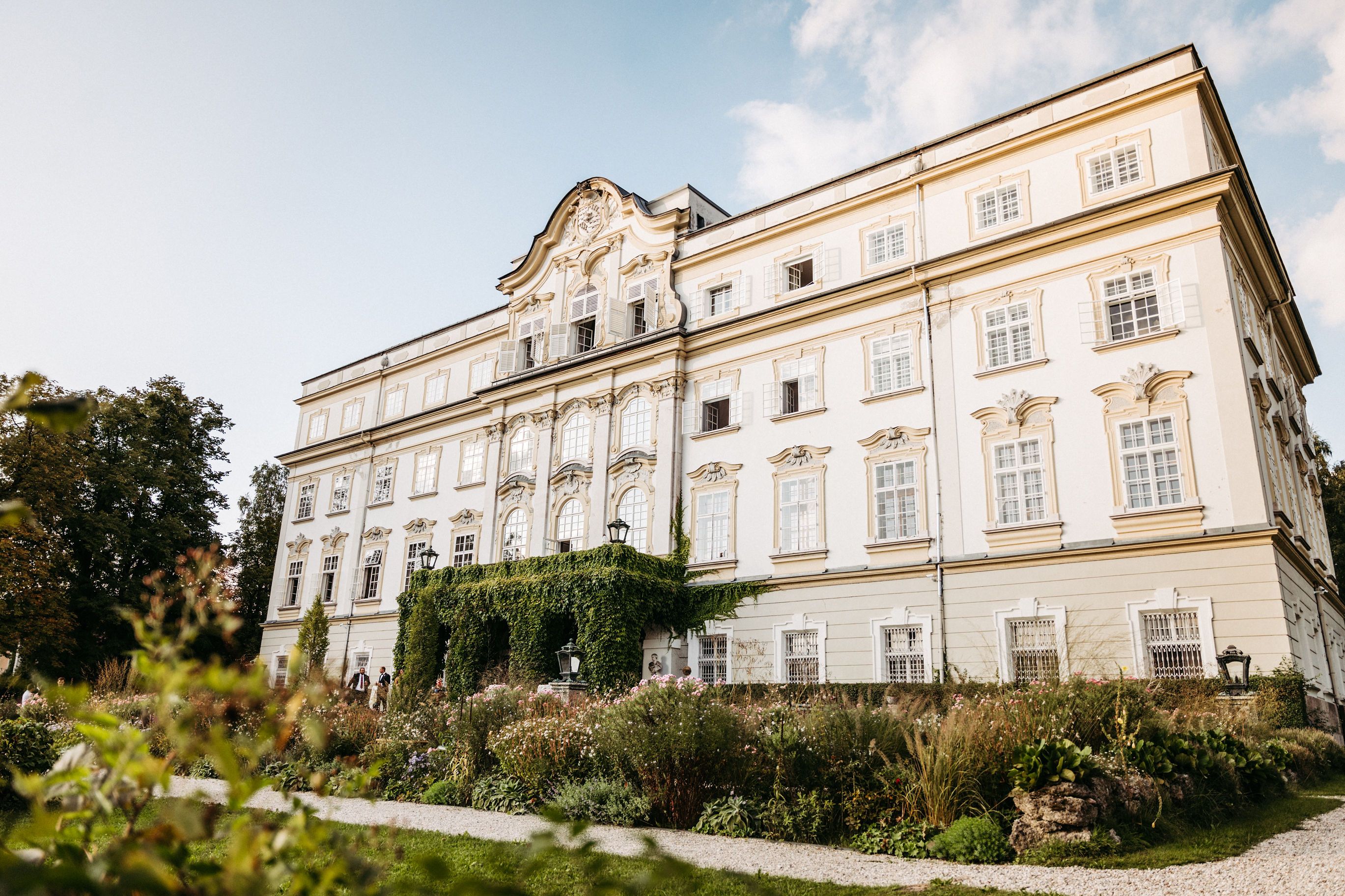 White classical castle with lush green gardens outside in Austria