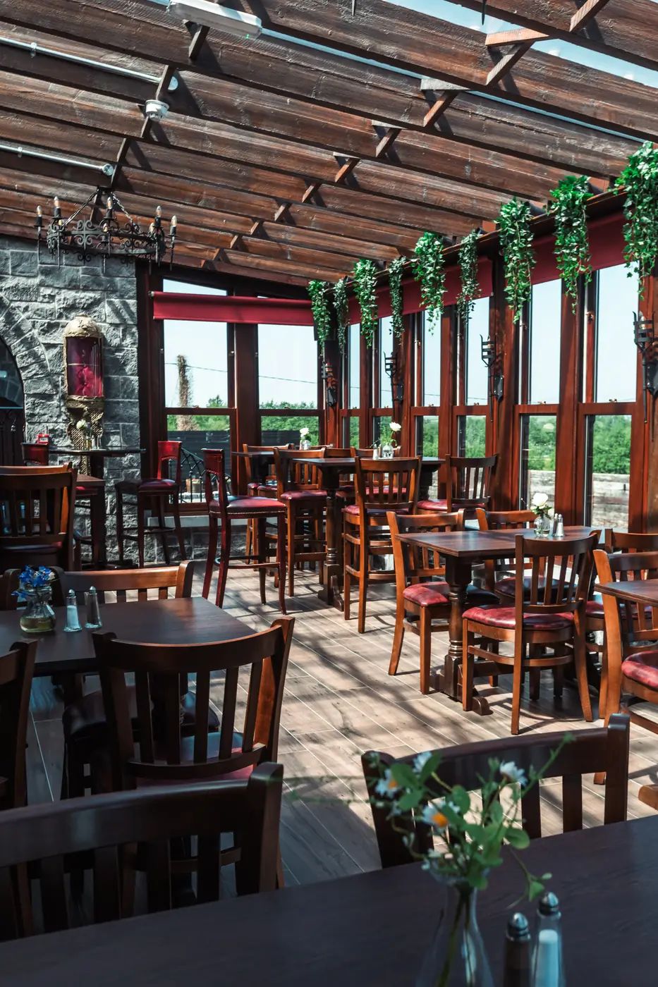 The Conservatory restaurant at Cloonacauneen Castle, a timber-slatted glass roof and red leather chairs looking onto fields.