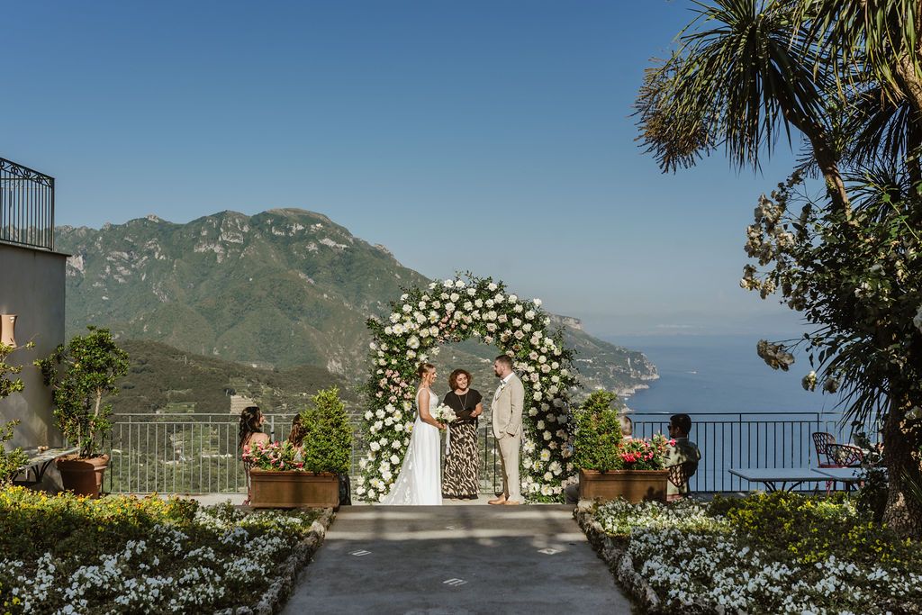 Bride and groom with their celebrant and guests during the ceremony of their Italian elopement atop a hotel in Amalfi