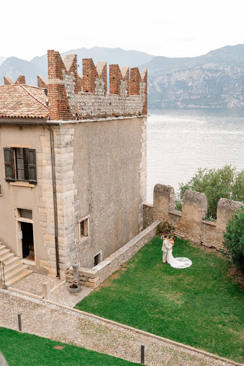 Couple having a romantic photoshoot at the grassy area beside the lakeside castle where they eloped in Italy