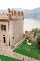 Couple having a romantic photoshoot at the grassy area beside the lakeside castle where they eloped in Italy
