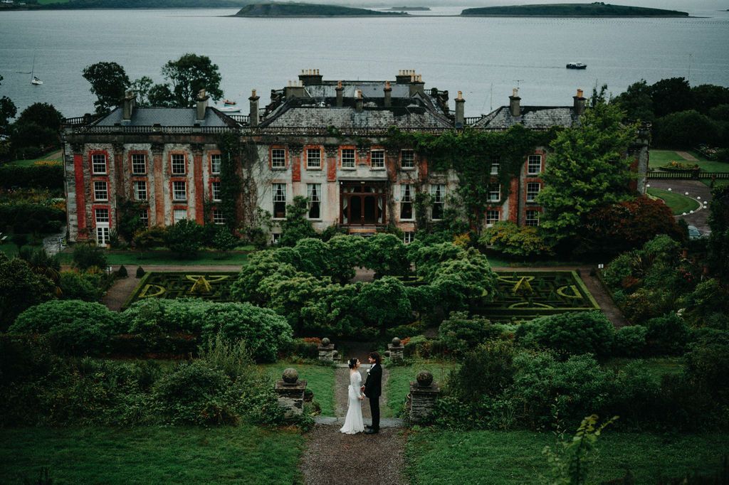 Historic building in Ireland that is partially covered in greenery, surrounded by lush green trees 