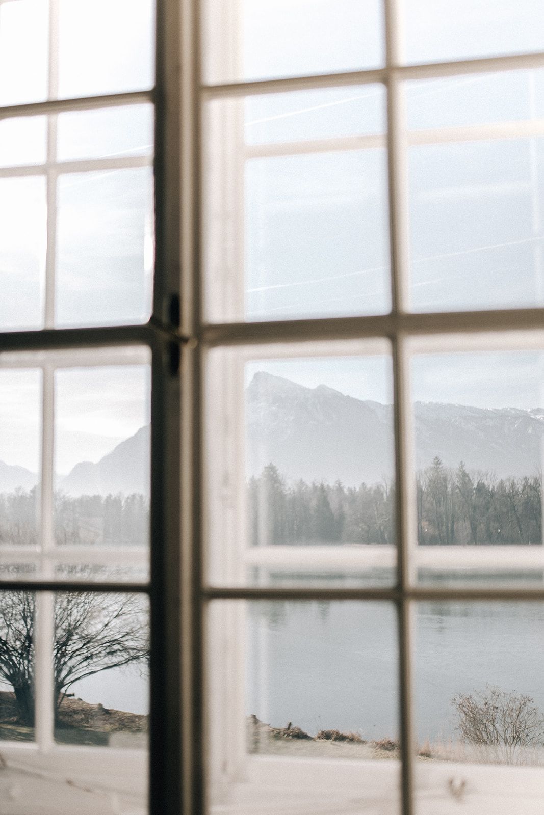 View through a paned window across a lake to hazy mountains near Salzburg
